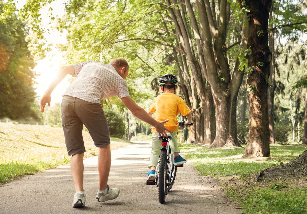 father helping child ride a bike